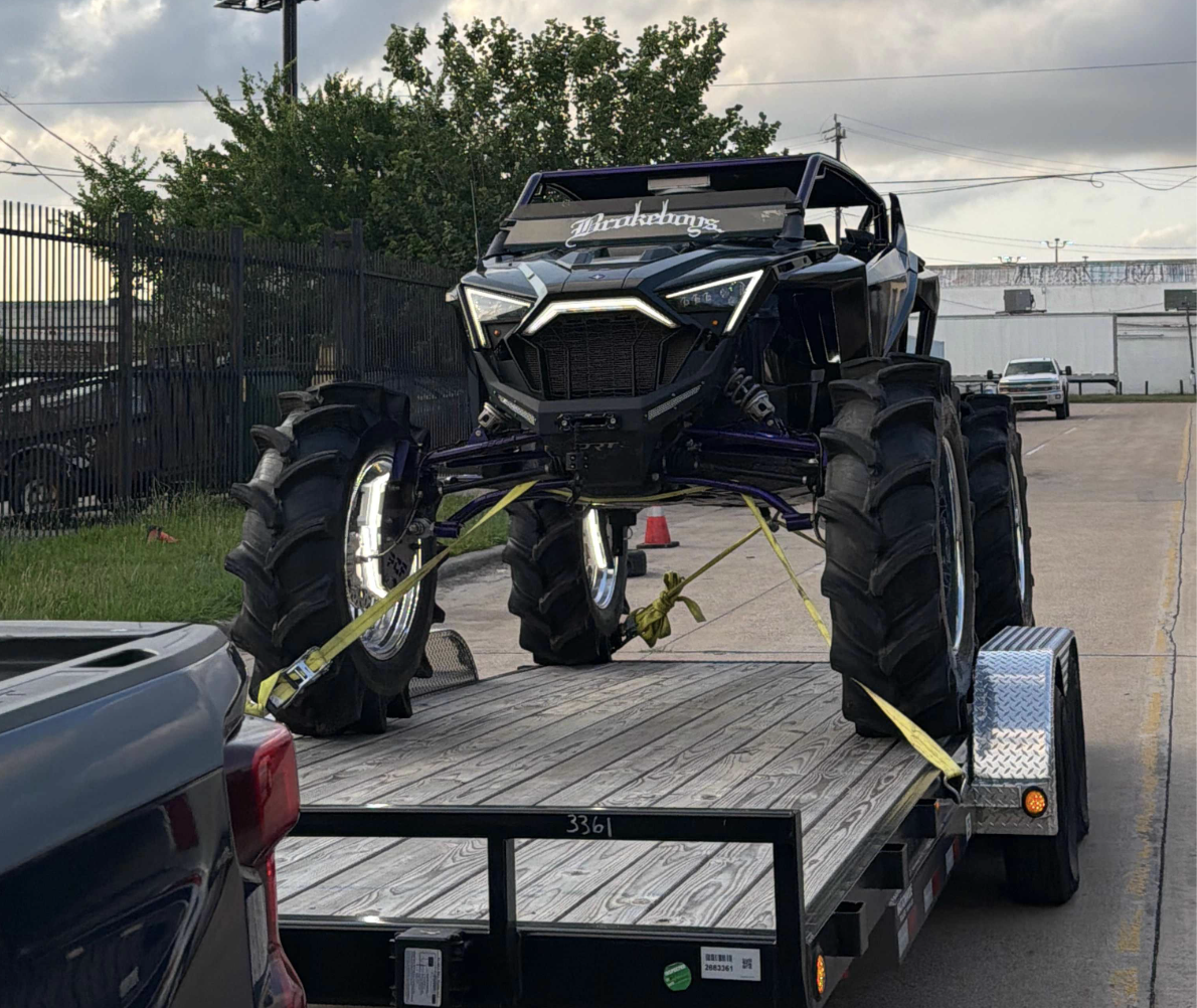 Flatbed trailer hauling a lifted off-road vehicle, available for rent from Lgv trailer rental and transport in Houston, Texas
